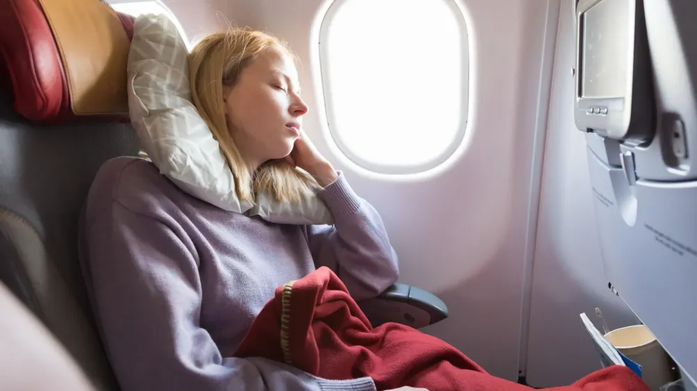 woman sleeping on plane in window seat